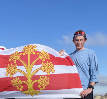 Matty Jackman stands atop Base Brown, proudly hoisting the County Flag of Westmorland, having completed all 214 Wainwright's (in 2021).